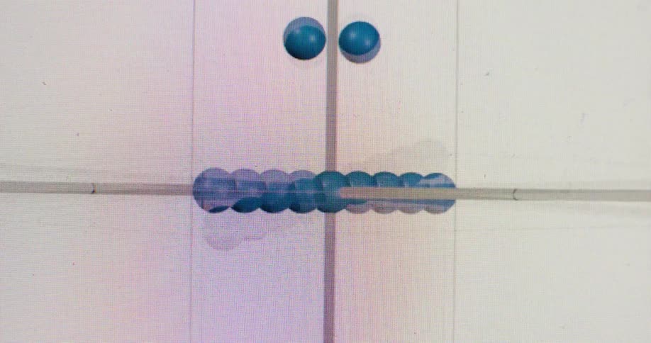 A macro shot of a computer screen shows an animated 3D plot with blue spheres moving along its axes