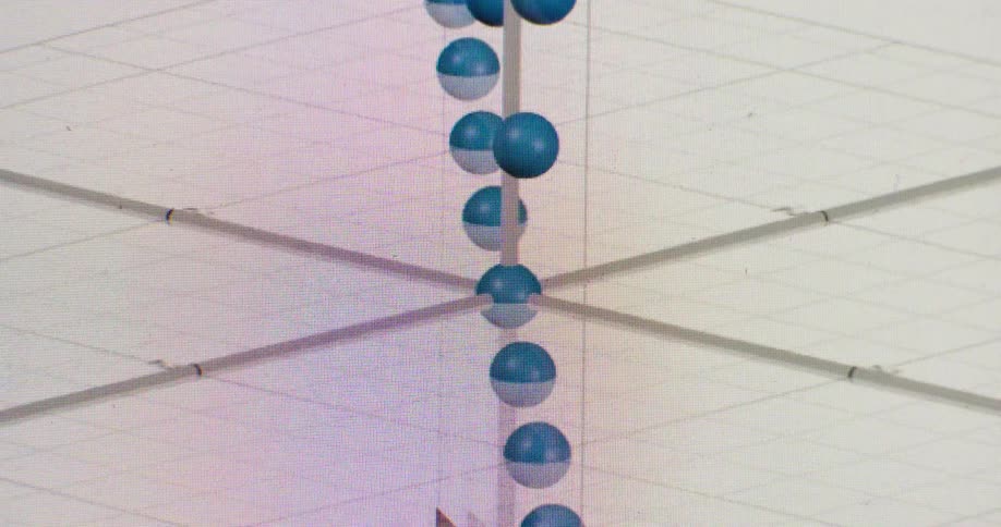 A user manipulates a 3D graph, rotating blue spheres plotted along X, Y, and Z axes on a computer screen