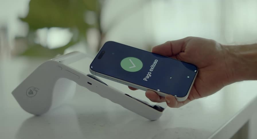 Close-up of a customer successfully completing a contactless mobile payment in Spanish on a modern white POS terminal