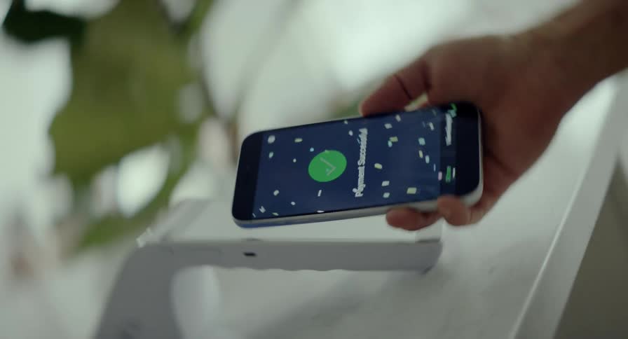 A customer makes a successful contactless payment with a smartphone, celebrated by a dynamic spinning animation and digital confetti