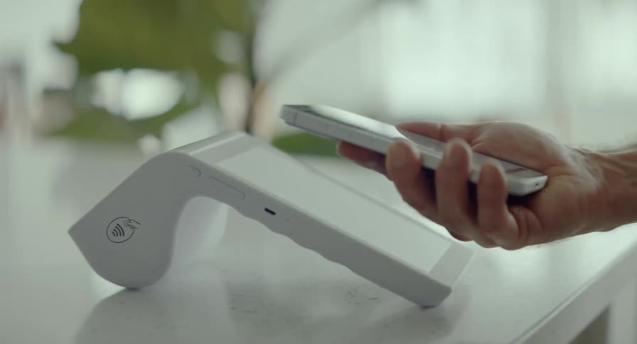 A customer makes a quick and easy contactless payment by tapping their smartphone on a modern POS terminal
