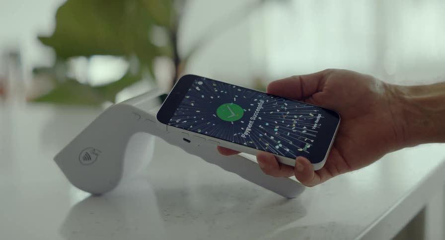 A celebratory animation confirms a successful contactless payment on a smartphone held over a payment terminal