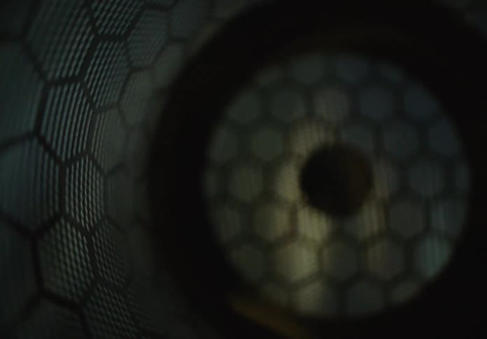 Hypnotic, abstract view of light flashing inside a metallic tube with a honeycomb texture