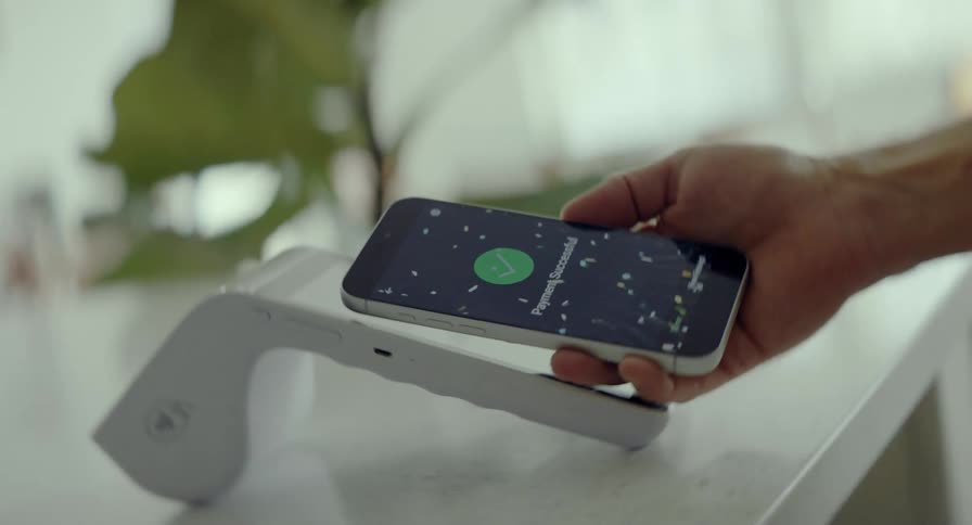 A person makes a successful contactless payment using a smartphone, with a celebratory animation appearing on the screen