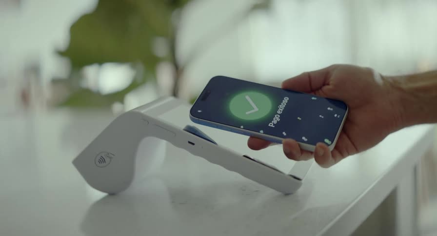 A rotating slow-motion shot shows a hand making a successful contactless payment by tapping a smartphone on a modern POS terminal