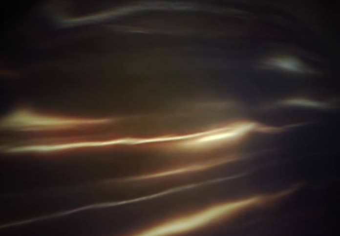 Warm, glowing light refractions dance hypnotically across a dark, mysterious background