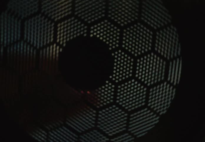 The mesmerizing interior of a spinning industrial drum creates an abstract light show through its hexagonal perforated surface