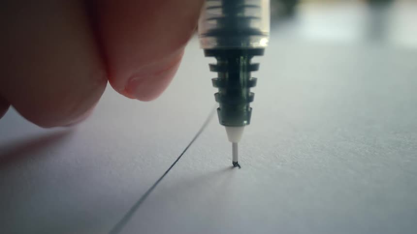 An extreme close-up macro shot of a fine-tipped ink pen drawing a continuous line across a white piece of paper