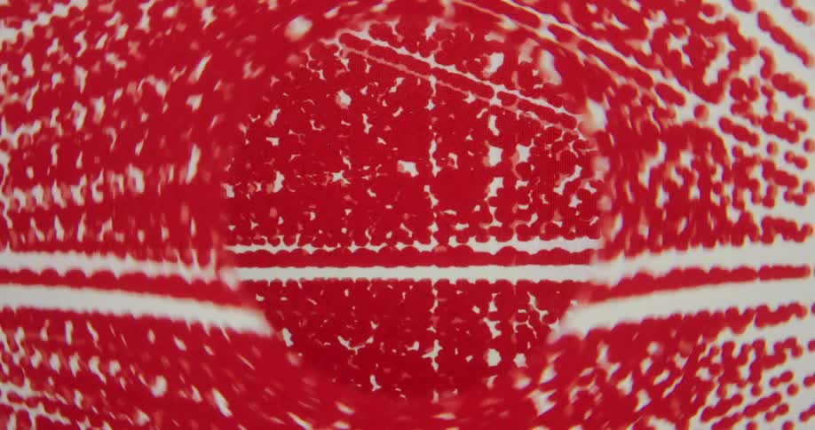 A close-up of a computer screen displays a mesmerizing, abstract red and white animated graphic