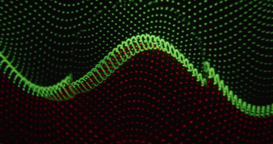 A mouse cursor interacts with an abstract display of moving red and green dotted wave patterns
