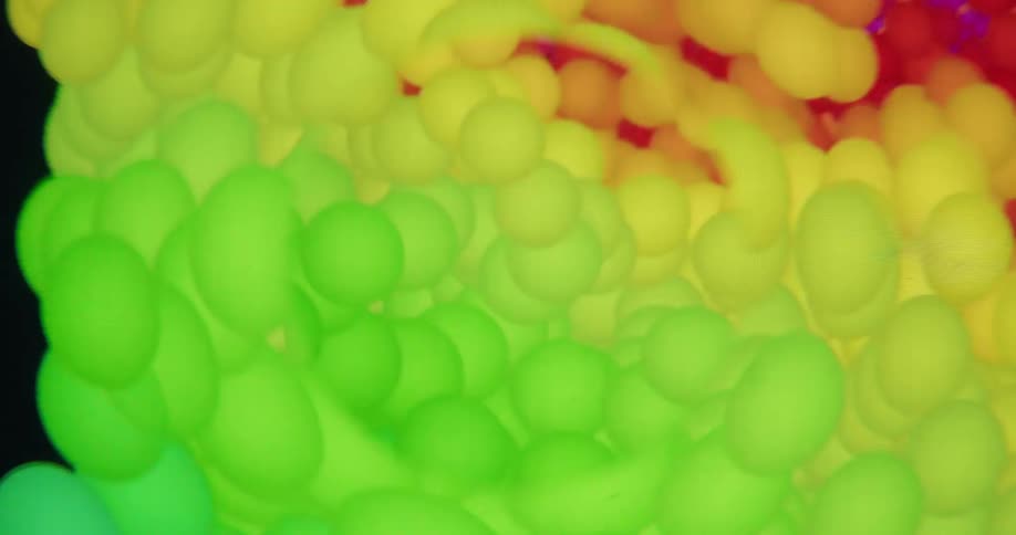 A swirling vortex of colorful, abstract particles shifts through a rainbow spectrum against a black background