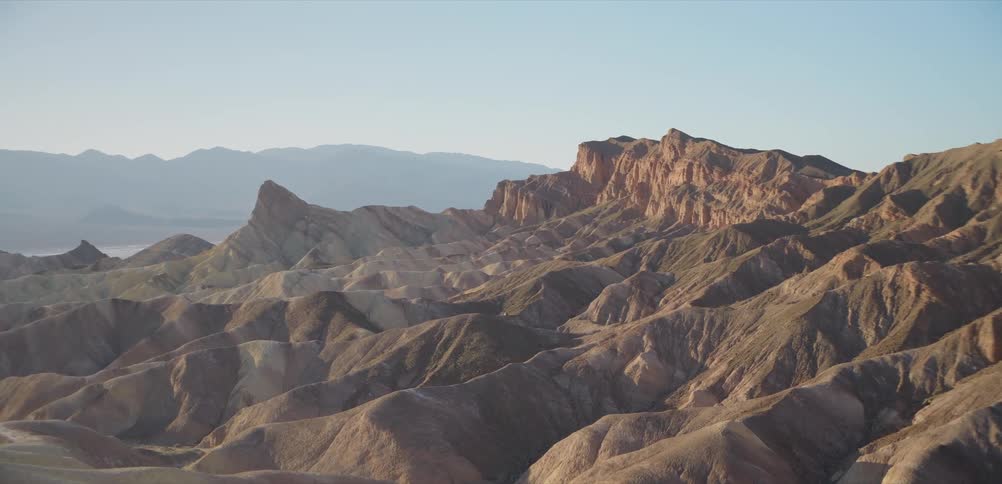 The rugged, eroded badlands of Zabriskie Point in Death Valley National Park glow in the warm morning light