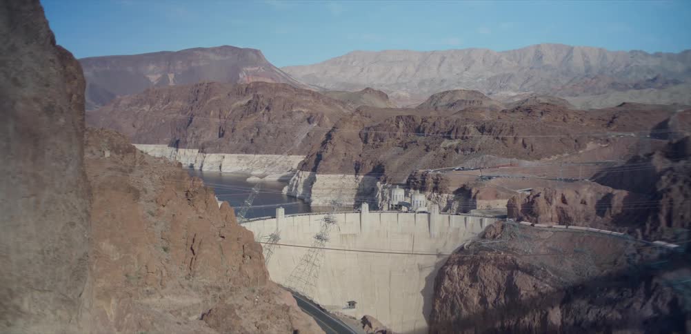A wide, high-angle view of the iconic Hoover Dam nestled within the arid, rocky canyons on a clear day
