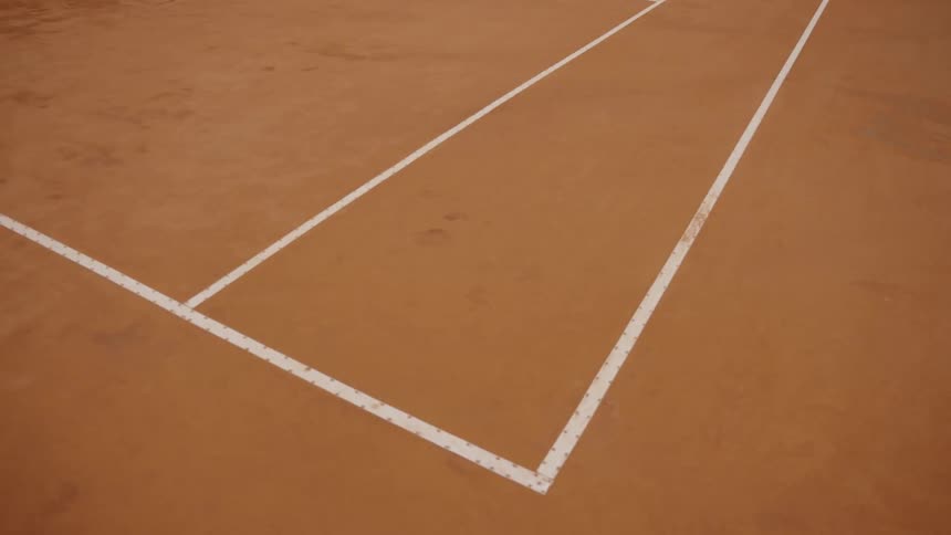 Static close-up shot of the corner boundary lines on an empty red clay tennis court