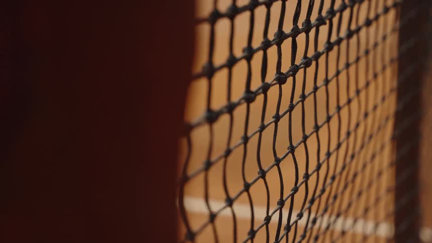 Close-up shallow depth of field shot of a tennis net on a clay court