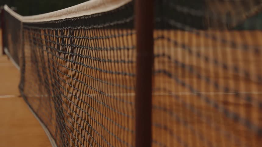 A shallow focus close-up of a tennis net on an empty clay court