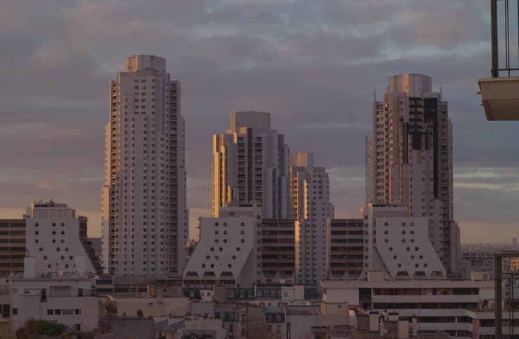The morning sun casts a golden glow on distinctive high-rise buildings in a quiet cityscape