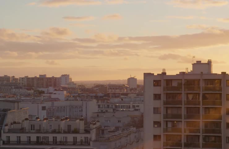 An aerial view pans slowly across the cityscape of Paris, France, as the warm sunset light washes over the buildings
