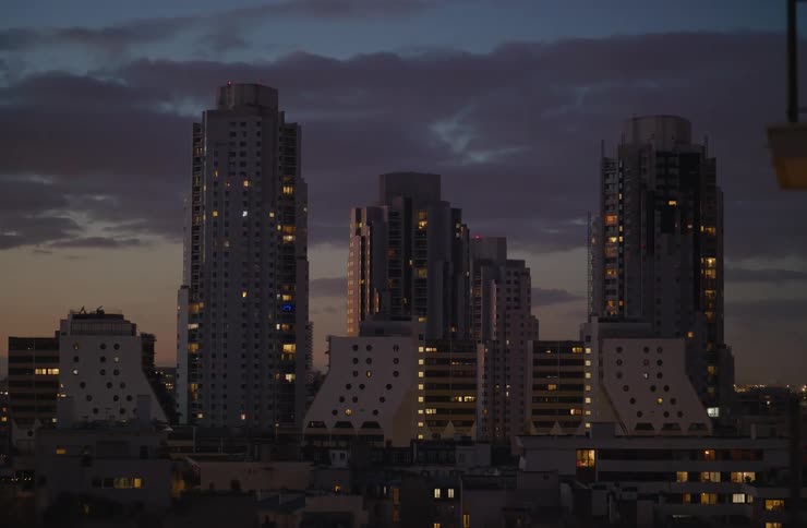 Modern apartment towers are illuminated against a cloudy sky at dusk in Paris, France