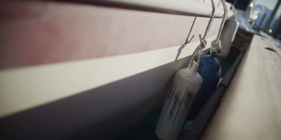 A close-up view shows a docked boat with weathered bumpers as it rocks gently in the marina's calm water