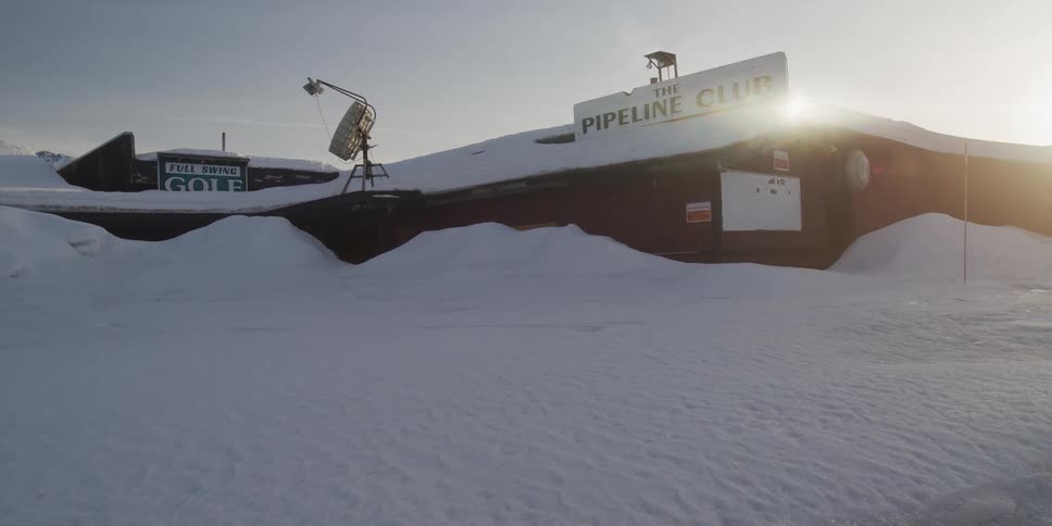 Time-lapse of the sun moving across the sky above The Pipeline Club, which is buried deep in snow