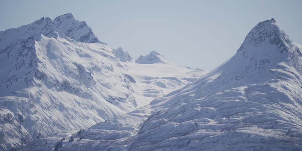 A slow pan reveals the rugged peaks and snowy valleys of a vast mountain range in winter