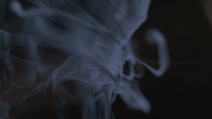 Ethereal plumes of white smoke dance and curl in slow motion against a solid black background