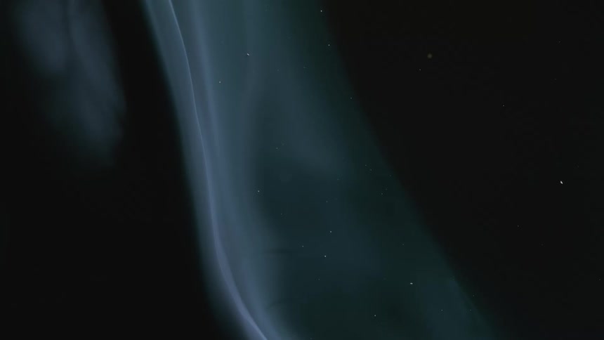 Ethereal blue-tinted smoke rises in a slow, graceful stream against a dark, mysterious background