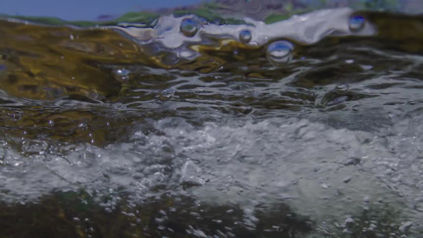 A mesmerizing slow-motion view from just below the surface of a turbulent, bubbling river