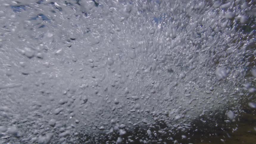 A seamless loop of churning water bubbles rising to the surface from an underwater perspective