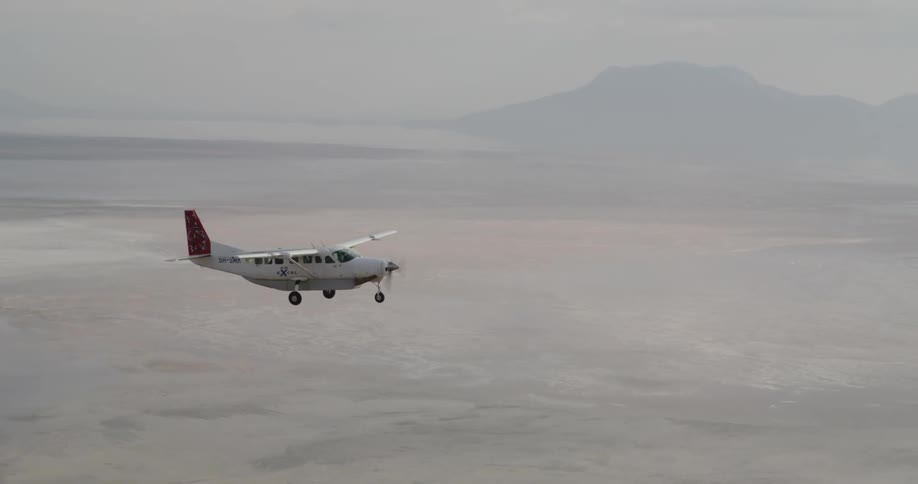 A plane flying through a misty sky near a mountain