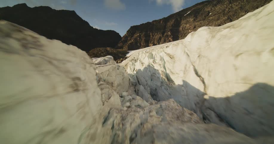 An epic aerial journey flies over a vast mountain glacier and dives deep into its icy crevasses