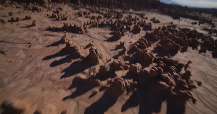An inverted aerial view flips and rotates into a breathtaking, fast-paced flight over the surreal rock formations of a desert valley