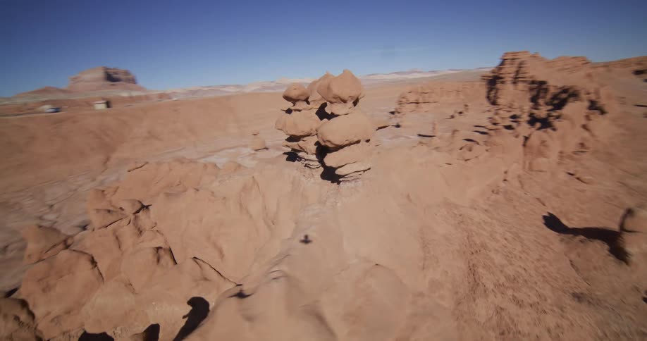 A first-person view drone flight circles a distinctive hoodoo rock formation in the arid desert landscape of Goblin Valley, Utah