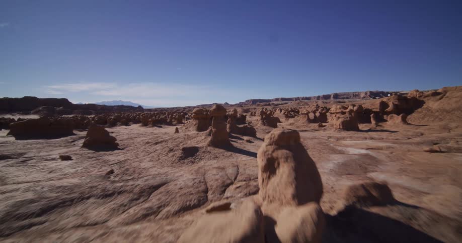 A smooth, low-altitude flight explores the strange and beautiful hoodoo rock formations of a vast desert valley under a clear blue sky