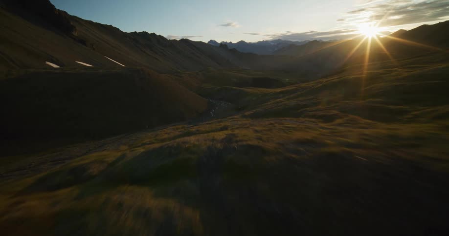 An exhilarating aerial flight through a vast mountain valley reveals a spectacular sunset over the rugged wilderness
