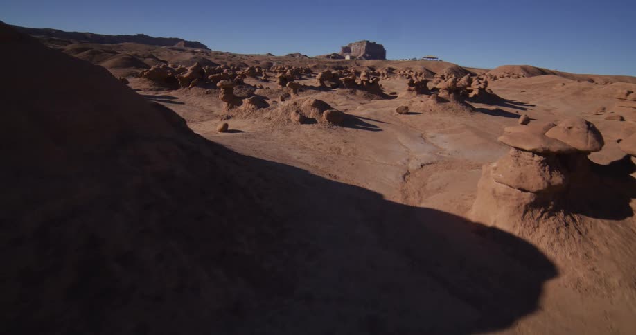 Sweeping aerial shot descends into the otherworldly landscape of Goblin Valley, filled with unique hoodoo rock formations