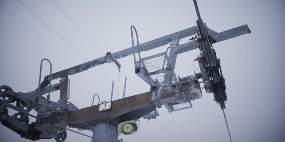 A slow-motion close up reveals the mechanics of a ski lift pylon operating in a snowy mountain landscape
