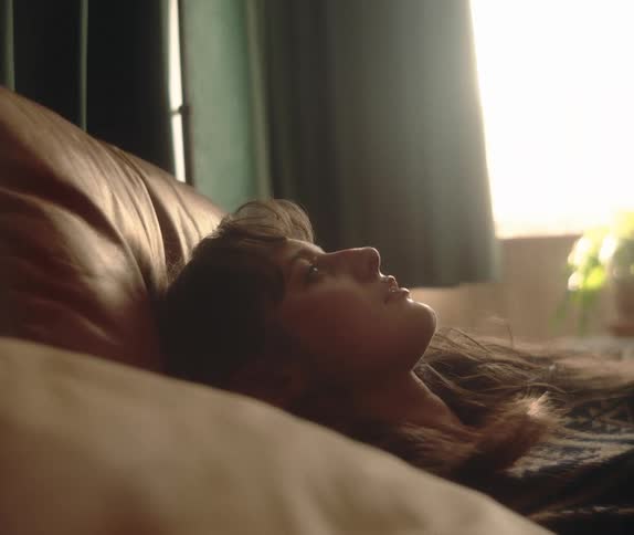 Serene close-up of a young woman sleeping in her bed, illuminated by gentle morning light