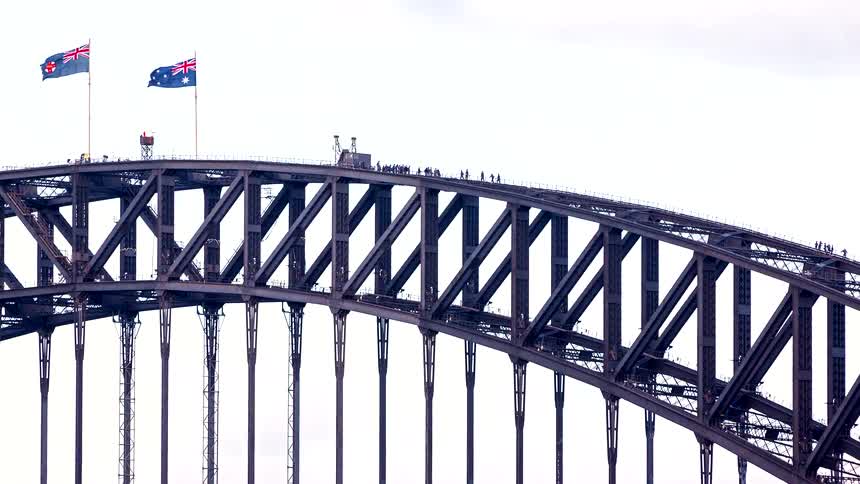 Tourists enjoy the BridgeClimb experience on the iconic Sydney Harbour Bridge as the Australian and New South Wales flags wave in the wind