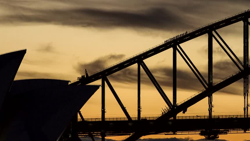 A stunning timelapse shows the silhouette of the Sydney Harbour Bridge and Opera House against a fiery sunset sky as clouds drift by