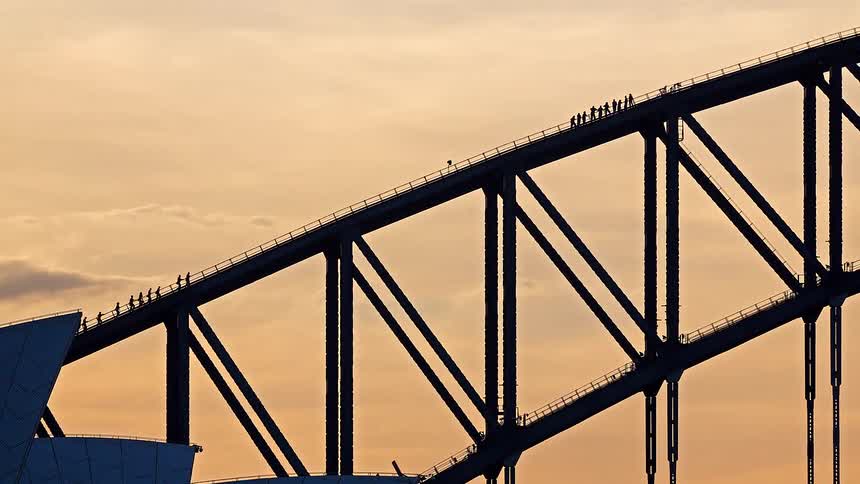 A dramatic timelapse zoom-out reveals the iconic Sydney Harbour Bridge and Opera House silhouetted against a golden sunset