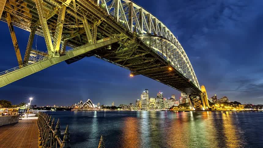 Stunning day to night time-lapse from under the iconic Sydney Harbour Bridge captures the city lights illuminating the skyline and Opera House