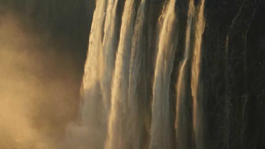 Sun-kissed water cascades down a majestic waterfall in a beautiful slow-motion close-up