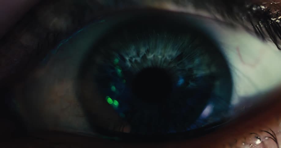 An extreme macro shot captures the intricate details of a human eye as the pupil dilates in response to changing light