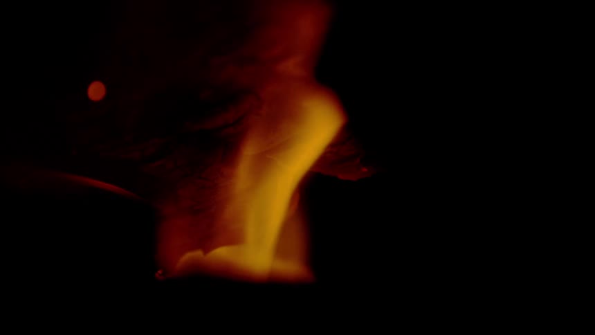 An intense macro shot of a flame slowly engulfing a piece of paper in super slow motion