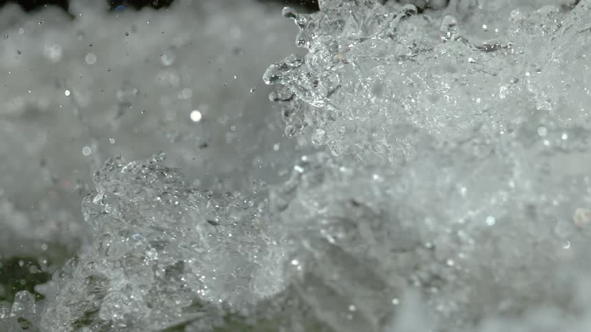 A mesmerizing close-up of turbulent river water churning and splashing in super slow motion