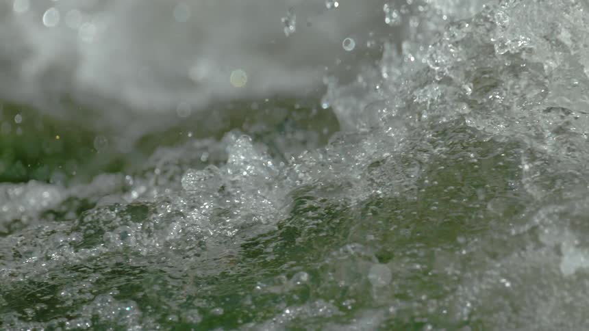 An extreme close-up shot captures the powerful, turbulent motion of whitewater in super slow motion