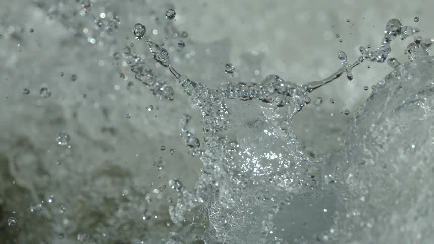 An extreme close-up of turbulent water splashing and sparkling in super slow motion