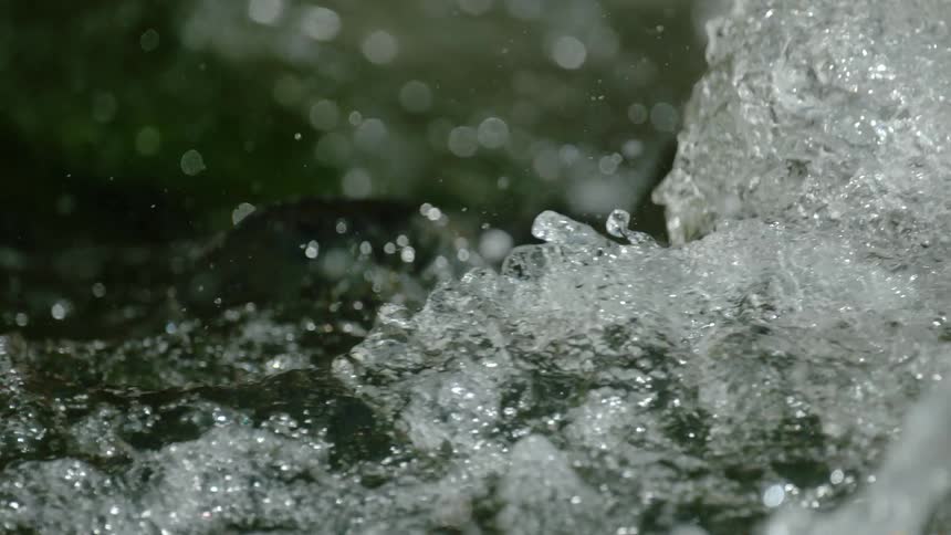 A close-up, slow-motion shot captures the dynamic and chaotic splashing of turbulent river water